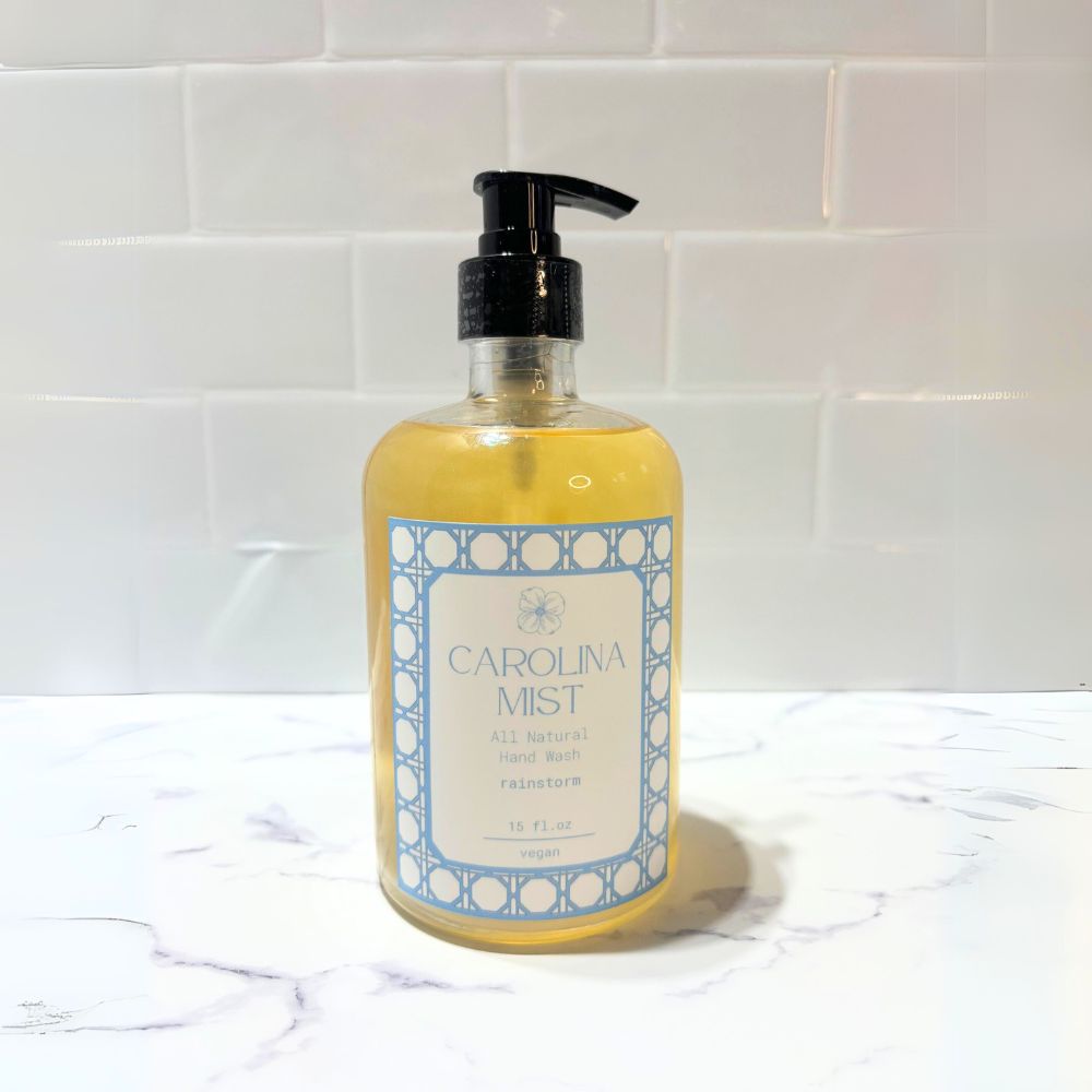 Carolina Mist Vegan Liquid Hand Soap in a clear recycled glass bottle, featuring Carolina blue packaging and a light rainwater scent. All-natural, eco-friendly, and luxurious