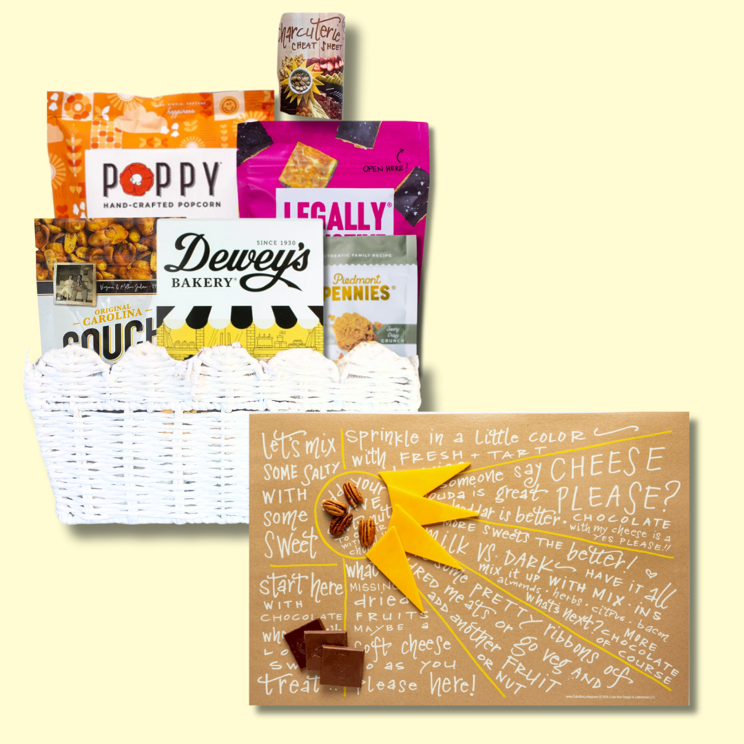 Sunburst Charcuterie Gift Basket with open cheat sheet against a light yellow background, highlighting NC-made gourmet treats like cookies, popcorn, and cheese wafers