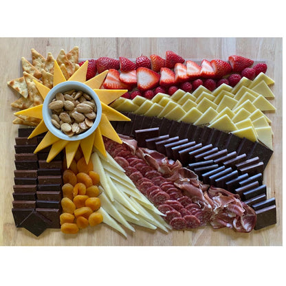 Completed charcuterie board using Sunburst Charcuterie Cheat Sheet with NC-made snacks, featuring cheese, crackers, and sweet and savory treats.