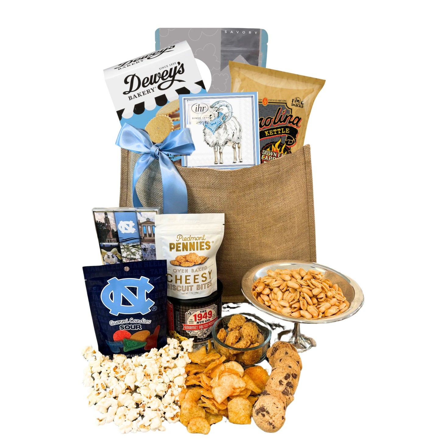 Gift Bag full of locally made in North Carolina products including Dewey's Vanilla Cookies, Carolina BBQ chips, Ellas Parma Amore Popcorn, Ram beverage napkins, Piedmont Pennies, UNC Sour gummies, UNC chocolates.