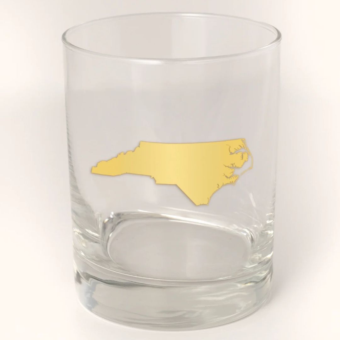 Empty 13.5oz cocktail glass with a 22k gold foil silhouette of North Carolina, displayed after the candle has been burnt, ready to be used as a stylish 'Old Fashioned' rocks glass.