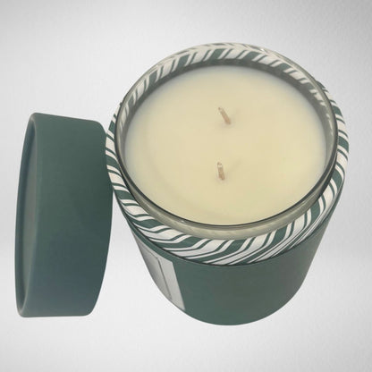 Top view of the Carolina Christmas candle inside its dark green tube, showing the top of the candle and the festive green and ivory candy stripes lining the inside of the packaging