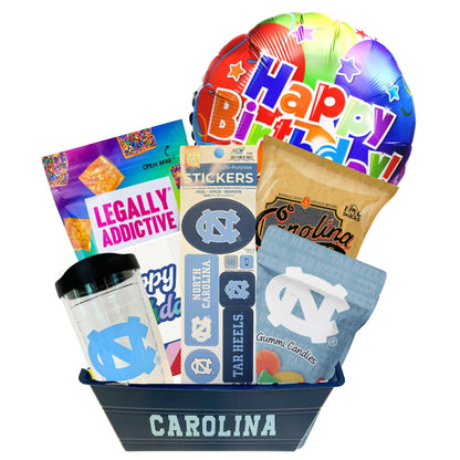 gift basket containing cookie cake, NC made Legally Addictive cookies, UNC stickers, UNC gummy candies, Carolina BBQ chips, and a UNC insulated cup to be delivered to UNC students at Chapel Hill.