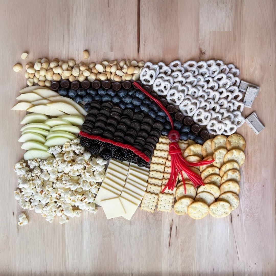 Fully assembled charcuterie board featuring NC-made gourmet snacks, including cheese wafers, chocolate cookies, caramelized hazelnuts, and yogurt-covered pretzels, perfect for graduation celebrations